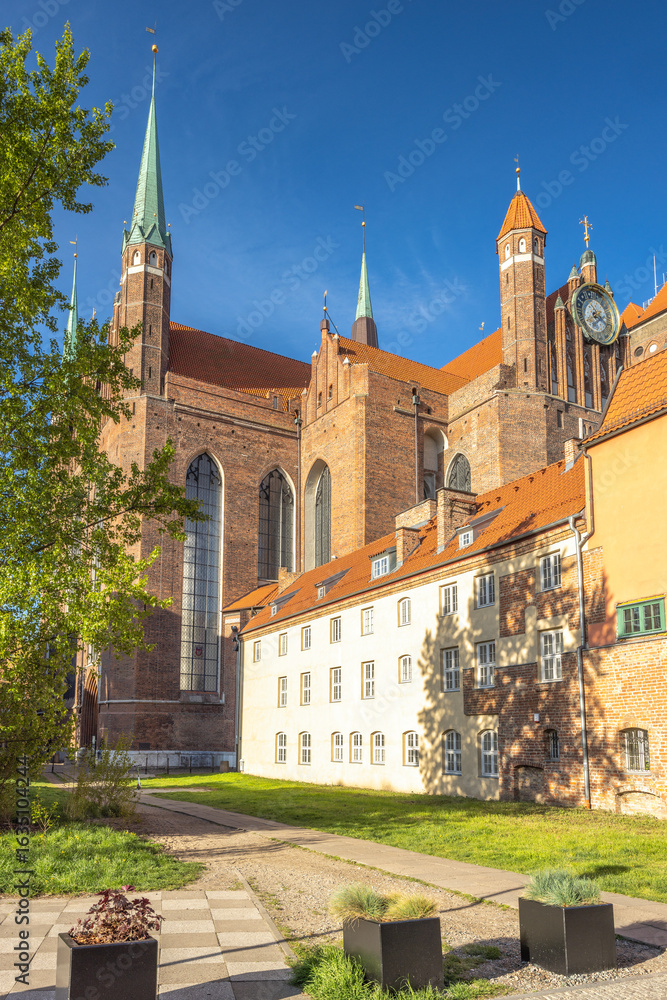 Fototapeta premium St. Mary's Church in Gdansk, a city on the Baltic coast of northern Poland, Europe. Historic cathedral with soaring spires, set against a clear blue sky, showcasing architectural grandeur.