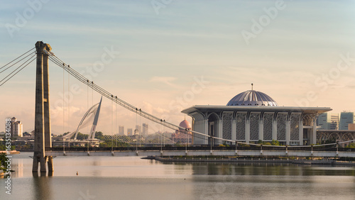 Golden hour over Putrajaya, Malaysia, featuring the iconic Seri Wawasan Bridge, Tuanku Mizan Zainal Abidin Mosque, and Putra Mosque. Modern architectural cityscape