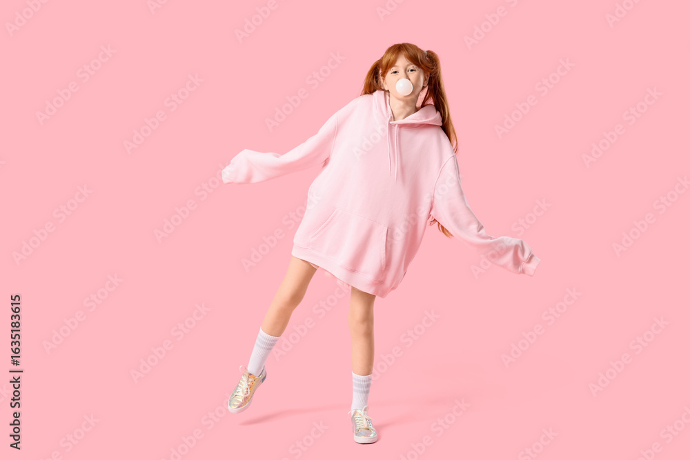 Cute ginger teenage girl blowing bubble gum on pink background Cute ginger teenage girl blowing bubble gum on pink background