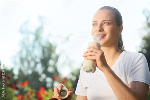 Sporty young woman drinking...