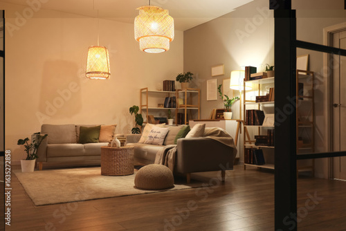 Interior of stylish living room with grey sofas, glowing lamps and bookshelve...