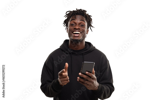 Smiling man in black hoodie points, holding phone. Use for social media or marketing.