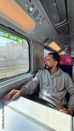 Man with beard dancing and looking out the window of a moving train