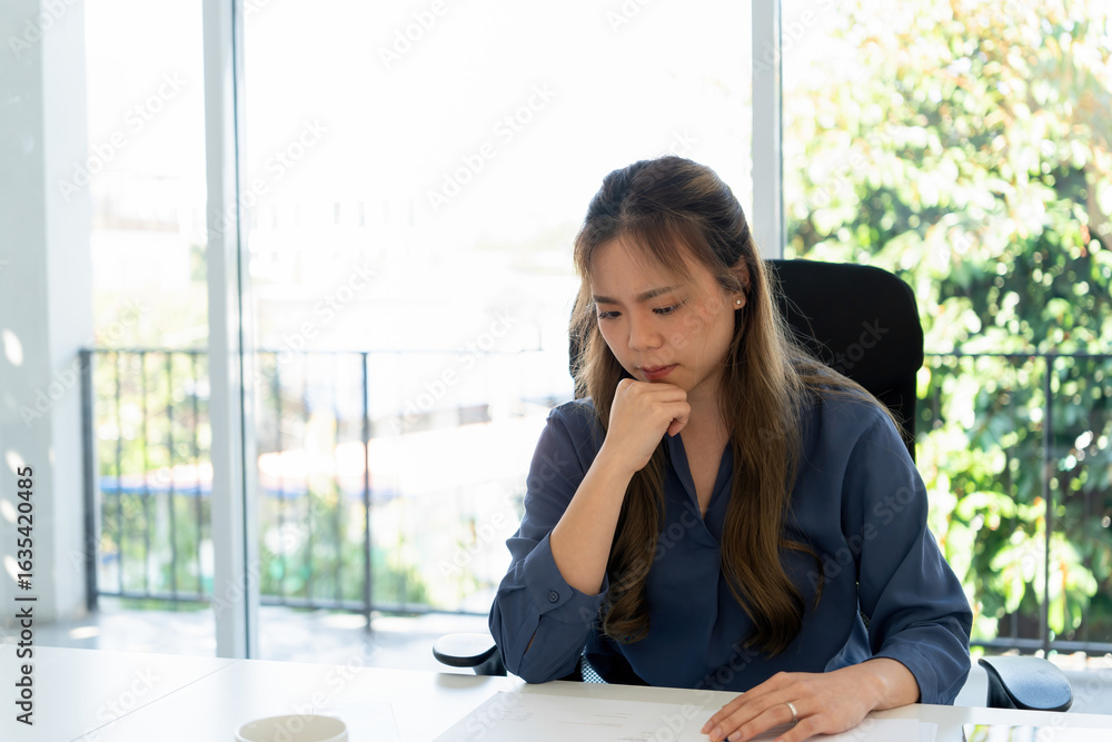 Obraz premium Businesswoman sitting at desk on couch in workplace or at home working on laptop and analyzing data on charts and graphs and writing on papers to make business plan and strategies for company.