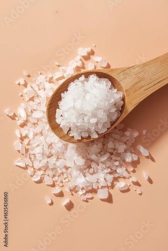 Coarse Sea Salt Crystals in Wooden Spoon on Gray Background