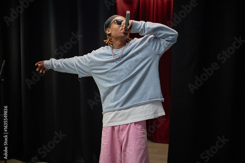 Obraz na plátne Black man performing on stage holding microphone wearing sunglasses participatin