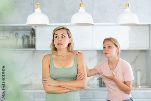 Agitated daughter imploringly asks angry mother for forgiveness. Concept of child rearing, generational conflict