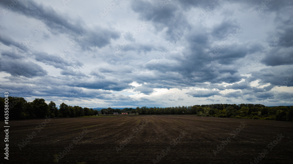 Obraz premium Dark cloudy sky over a plowed field 