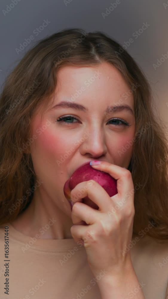 Portrait of Young Woman Eating Healthy Food as Looking at Camera Close Up. Vegan Person Bites Red Color Apple Relaxing in Joy. Appetite Concept of Hunger Lady with Ripe Farm Treat Inside Room Interior