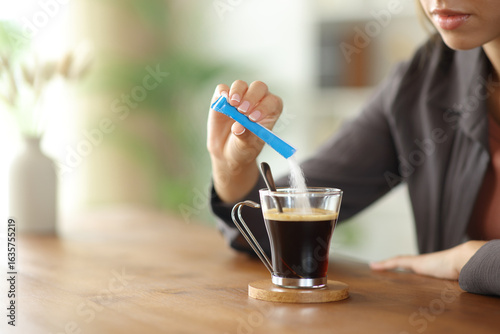 Принти на полотні Woman hand throwing sugar in a coffee cup on a table at home