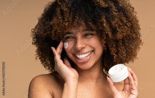 Canvas Print Beautiful black woman applying face luxury sunscreen or moisturizer cream for pe