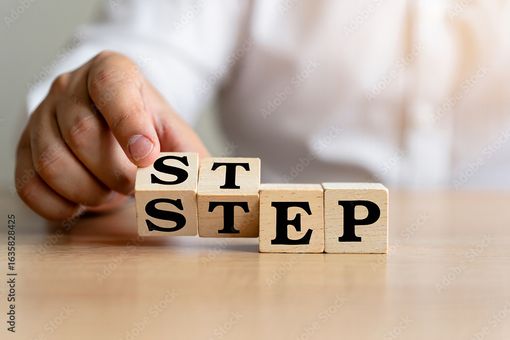 Naklejka premium Hand arranging wooden blocks spelling out the word step