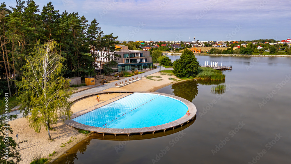 Fototapeta premium unique swimming pool built into Lake Słupeckie in Słupca, surrounded by forest, beach, and modern facilities. Combination of natural lake and recreational area.