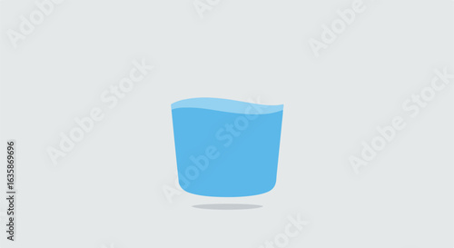 Glass of water standing on a plain surface, against a light grey background