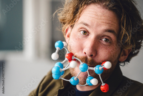 Man holding molecular model in mouth at home loft portraying science