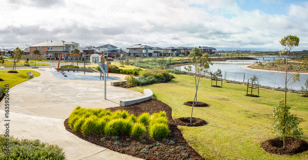Obraz premium Lakeside public park with basketball court, walking paths and landscaped greenery in suburban residential neighborhood of Melbourne, Australia. Concept of community recreation, outdoor sports