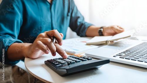 Doing finance, budgeting and tax calculation. Close up woman hand using calculator to calculate home finance, accounting with laptop computer on table, budget management, monthly expenses.