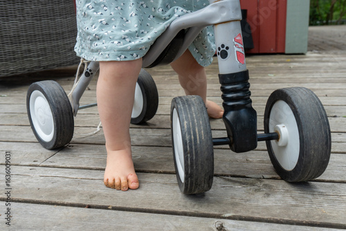 Foto Child riding a tricycle on a wooden deck outdoors.