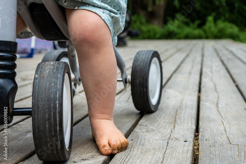Quadro su tela Child riding a tricycle on a wooden deck outdoors.