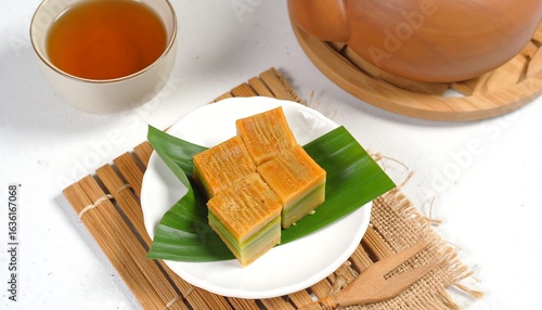 Slices of traditional Indonesian kue lapis legit served on a white ceramic plate, paired with a warm cup of tea.