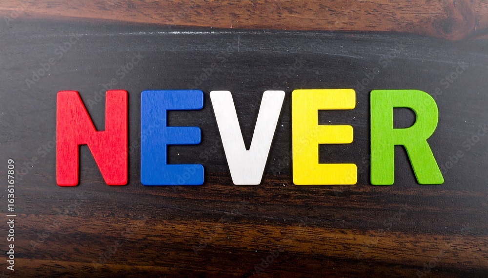 Fototapeta premium Colorful wooden letters spelling NEVER on a dark wood surface