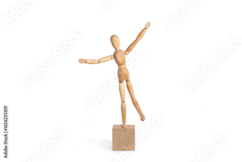 A wooden mannequin standing with one foot on a wooden block isolated on a white background