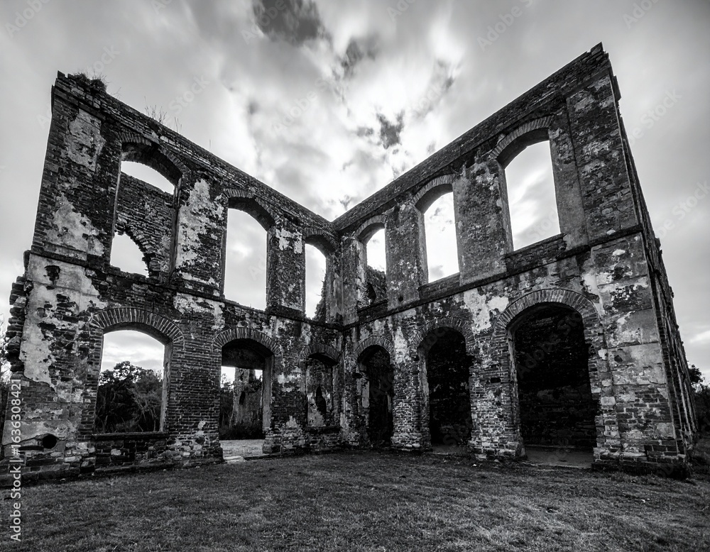 Fototapeta premium Black and White Dramatic Photo of Abandoned Historic Building Ruins with Cloudy Sky