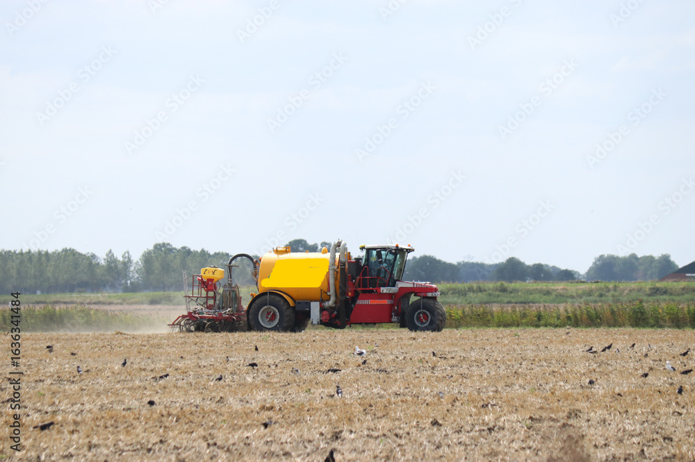 Obraz premium a hydro trike is fertilizing a bare field with slurry in the countryside in summer