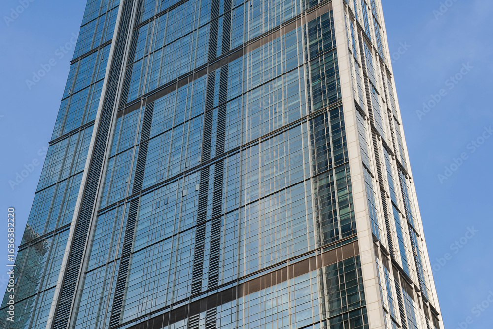 Obraz premium Low angle view of skyscraper with glass window and clear blue sky background for business and finance concept