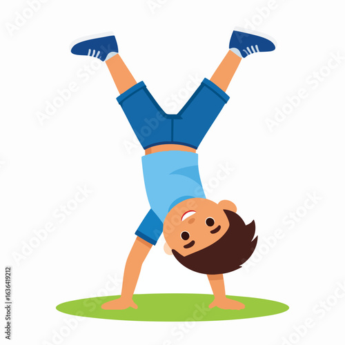 A young boy is doing a handstand on a green patch, with his legs up in the air.