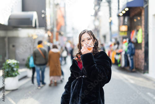 都会の路地でドリンクを楽しむ若い日本人女性