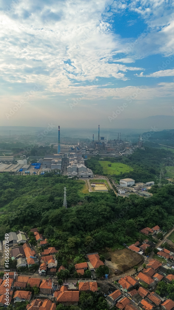 Fototapeta premium Aerial drone view of a large industrial factory complex with warehouses, chimneys, and storage tanks in Asia