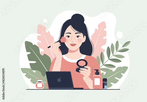 Young woman applying makeup with a brush while looking at a laptop, surrounded by beauty products and plants, suggesting an online tutorial or beauty routine