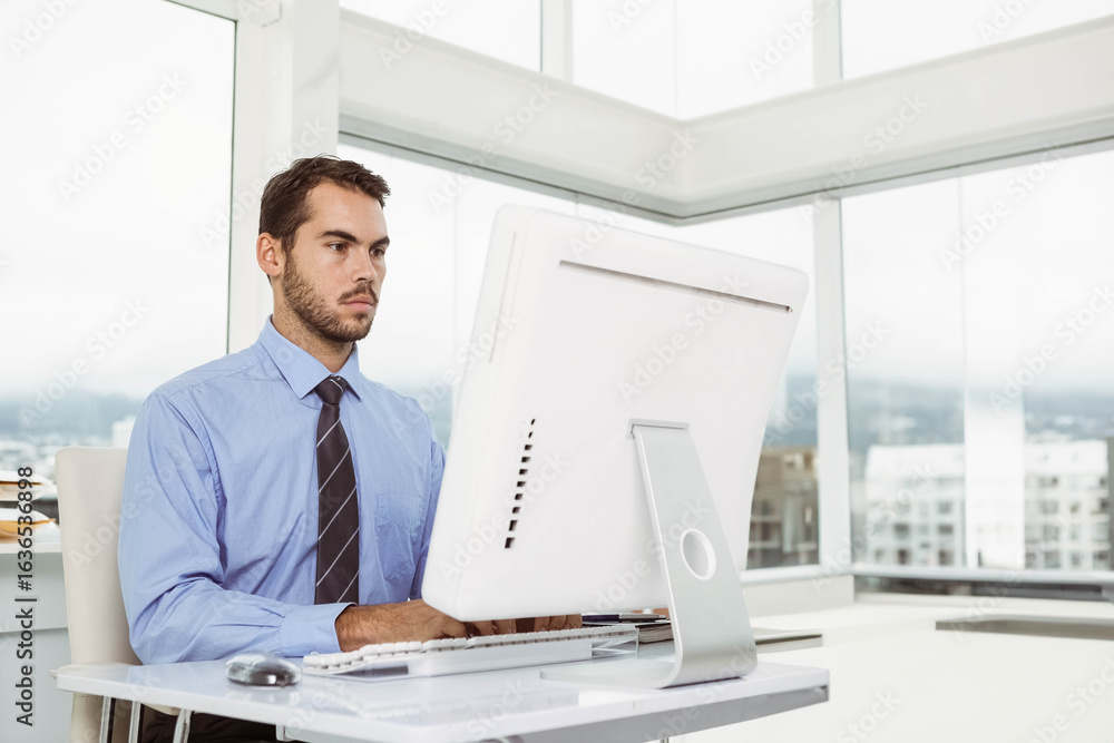 Fototapeta premium Businessman typing on all-in-one desktop computer in office corner with stack of papers, copy space