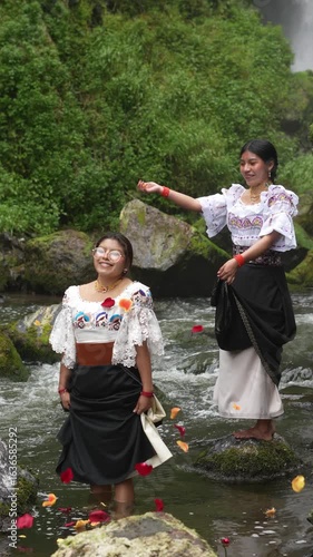Indigenous women celebrating with flower petals in a river