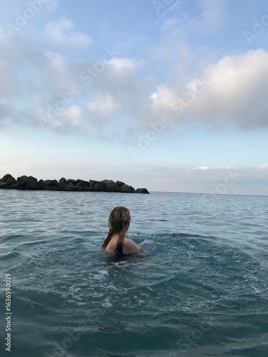 Young woman swimming in the crystal-clear Mediterranean waters.
