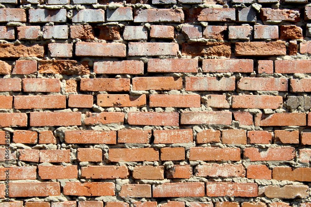 Obraz premium An old brick wall that is crumbling over time.