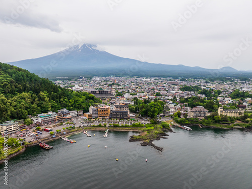 Aerial view of Mount Fuji majestically presiding over the tranquil waters and the town, creating a stunning contrast of natural and urban landscapes, Fujikawaguchiko, Yamanashi, Japan.