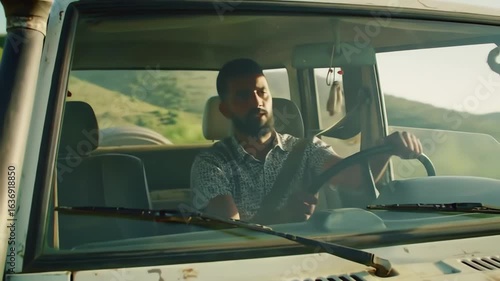 A bearded man driving his vintage off-road vehicle on a sunny country road journey