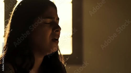 A beautiful woman sings a soulful song with her eyes closed in a warmly lit room