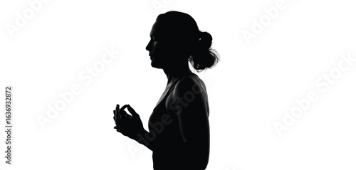 Silhouette of a woman with her hair in a bun spraying perfume