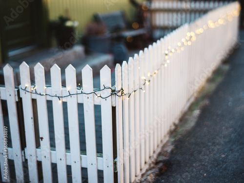 Charming White Picket Fence Adorned with Warm Festive String Lights Outdoors