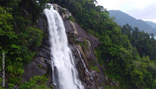 Majestic waterfall cascading down rocky cliff face in lush jungle