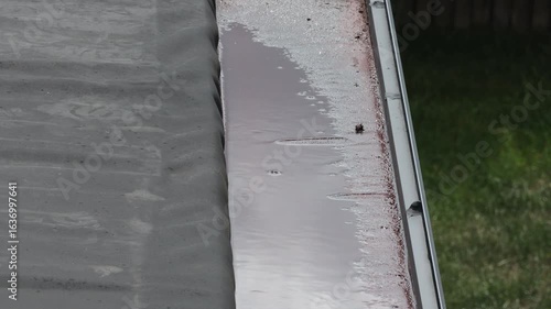 A residential house rain gutter clogged with dirty, stagnant water and sludge, indicating a blockage that requires cleaning and home maintenance