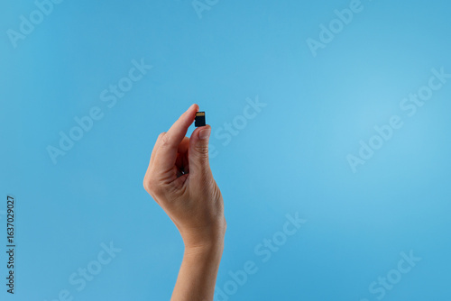 Quadro su tela Hand holding SD card on blue background useful for tech startups, digital market