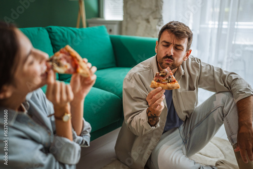 Fotografía Couple enjoying pizza on living room floor: eating together at home