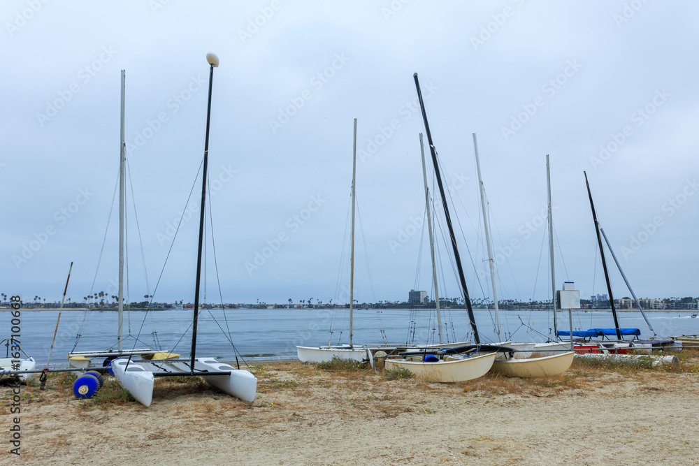Fototapeta premium Catamarans and other vessels on a sand of boat beaching area of Sail bay, San Diego, California