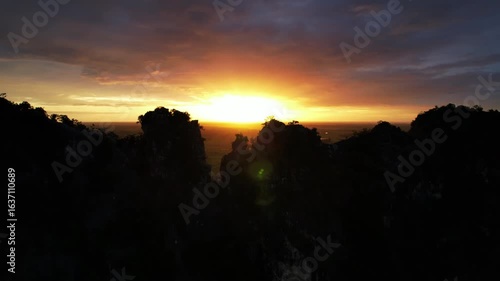 Wallpaper Mural  Beautiful aerial view of a mountain silhouette at sunrise, with the first light of the day breaking through the peaks and illuminating the colorful sky in shades of orange Torontodigital.ca