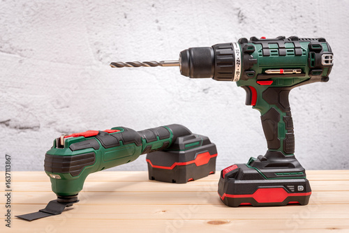 Cordless drill and electric multi-tool on wooden background