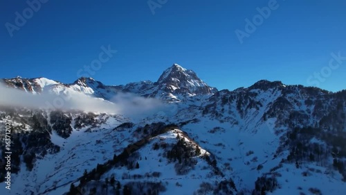 Snowy Mountain Peaks And Clouds Under Bright Clear Blue Sky